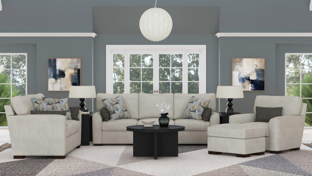 A modern living room featuring a neutral-toned sectional sofa with matching armchair and ottoman, adorned with patterned throw pillows. A round black coffee table sits in the center, flanked by two black side tables with table lamps. The walls are painted in a muted blue-gray tone, complemented by abstract artwork and large windows allowing natural light to filter in. A geometric area rug ties the space together.