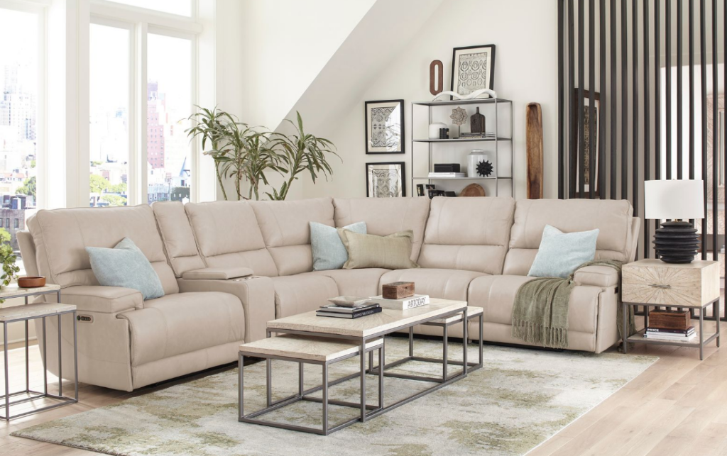 Light neutral Parker House 6-piece reclining sectional styled in a bright living room with soft pillows and a throw blanket.