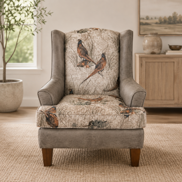 Rustic wingback accent chair with pheasant patterned upholstery and neutral faux leather arms in a warm living room setting