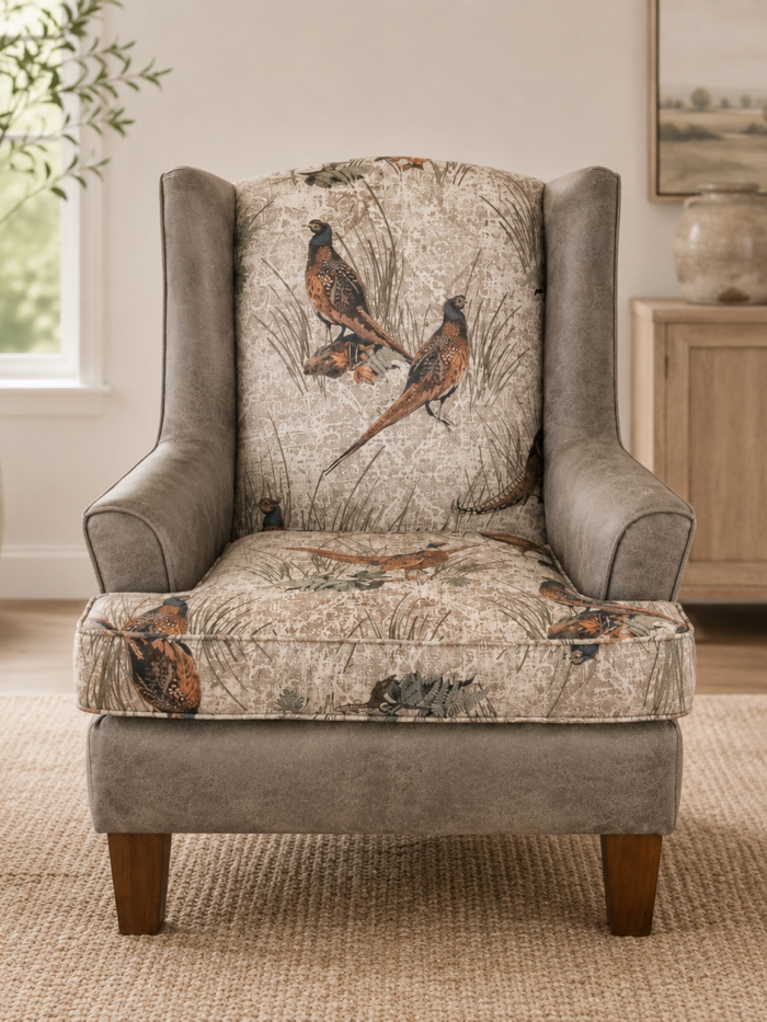 Rustic wingback accent chair with pheasant patterned upholstery and neutral faux leather arms in a warm living room setting