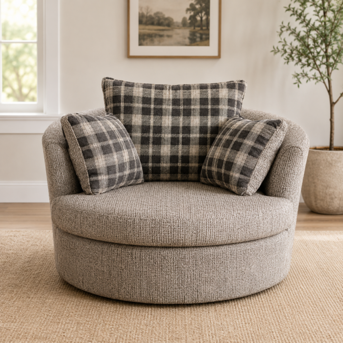Oversized round swivel accent chair with textured gray upholstery and plaid accent pillows in a warm neutral living room