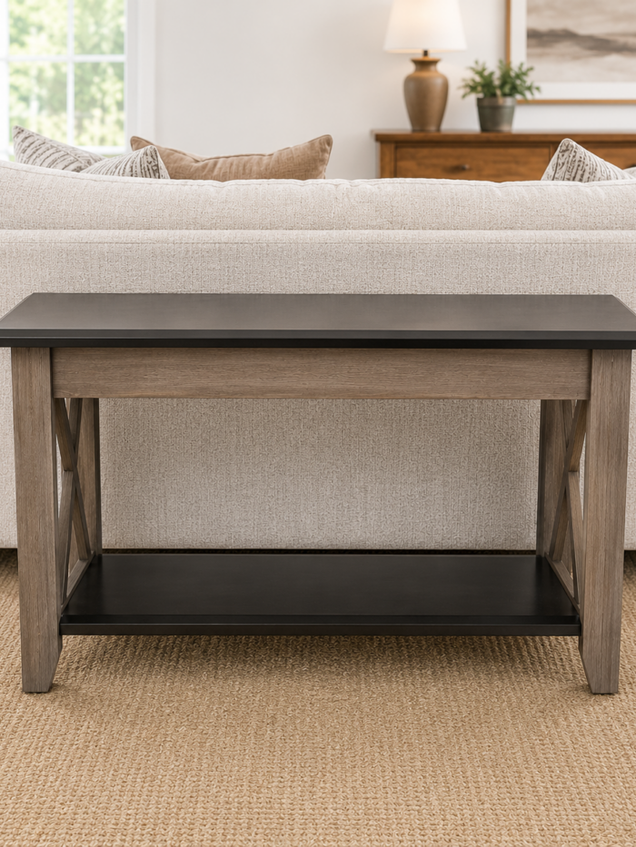 Rustic two-tone sofa table with lower shelf and X-frame side accents placed behind a light-colored sofa