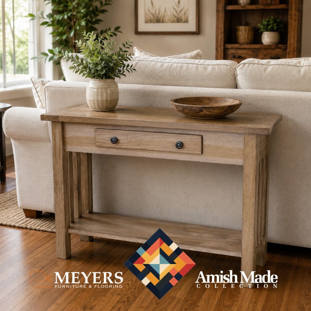 Amish-made wood sofa table with drawer and lower shelf behind a neutral sofa