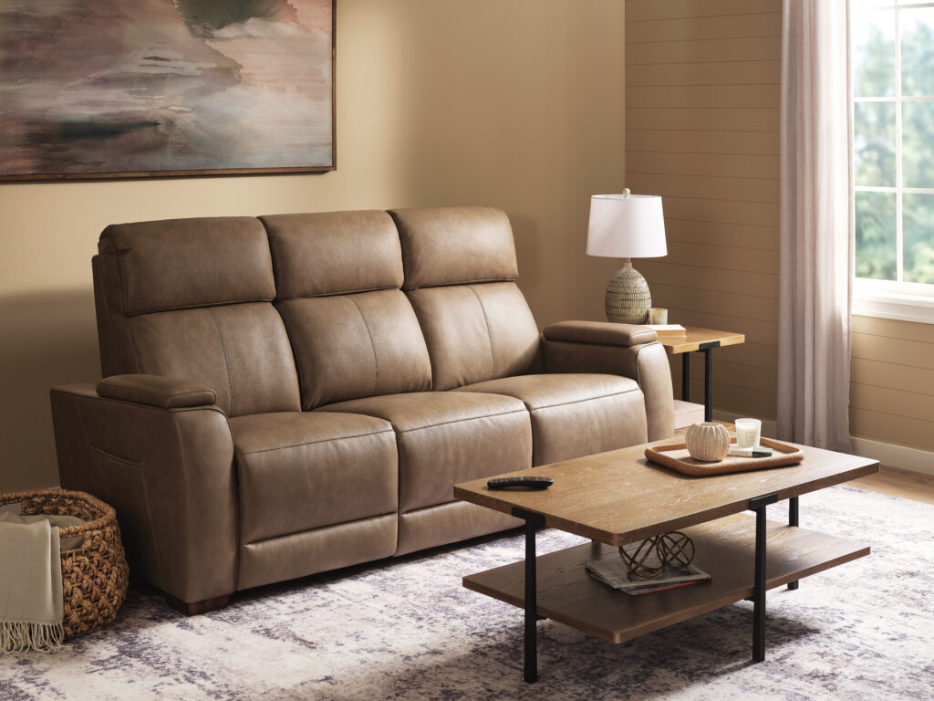 Flexsteel Pulse power reclining sofa in warm brown upholstery displayed in a styled living room with coffee table and side table.